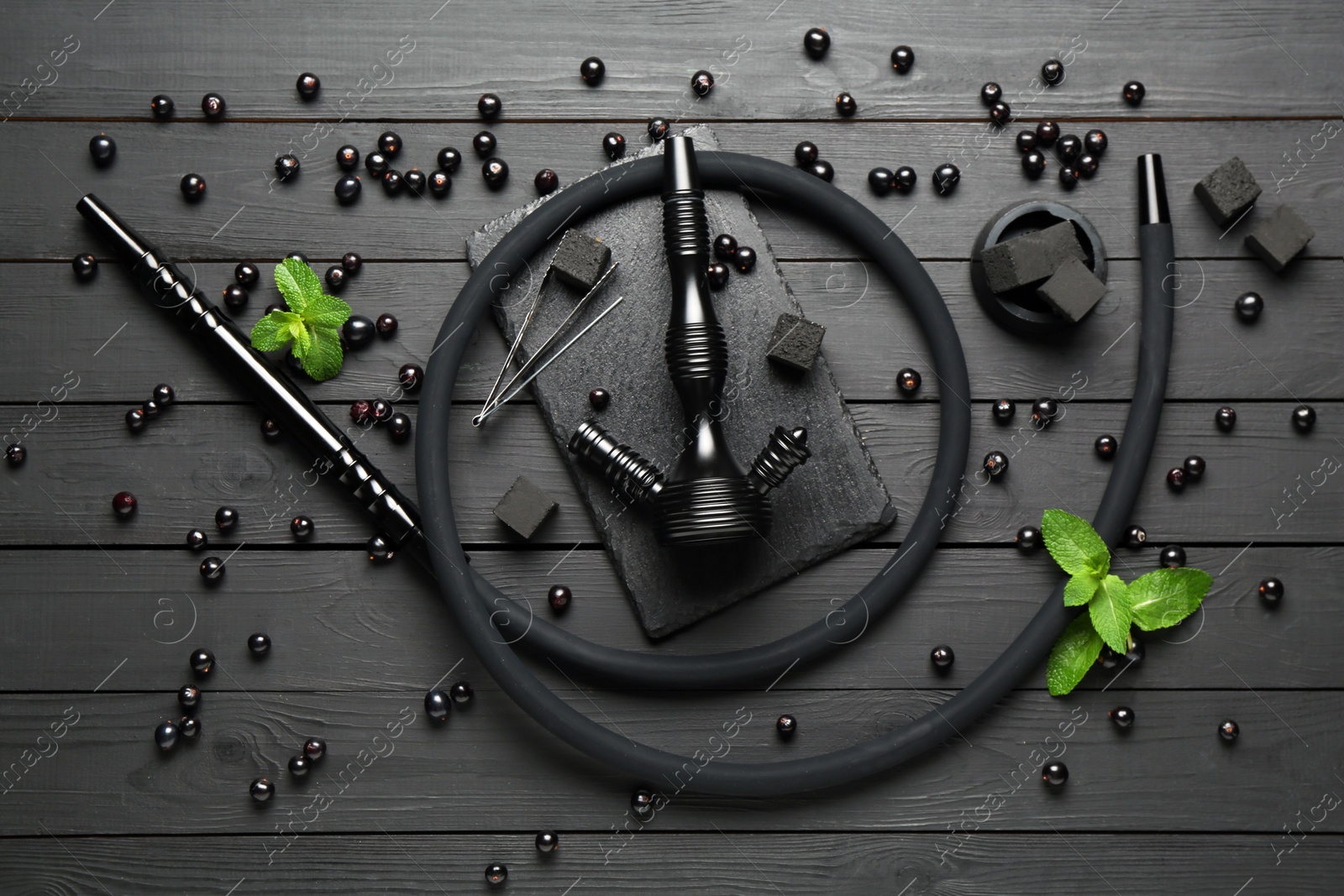 Photo of Hookah, coal, mint and currants on black wooden table, flat lay