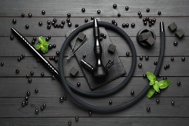 Photo of Hookah, coal, mint and currants on black wooden table, flat lay