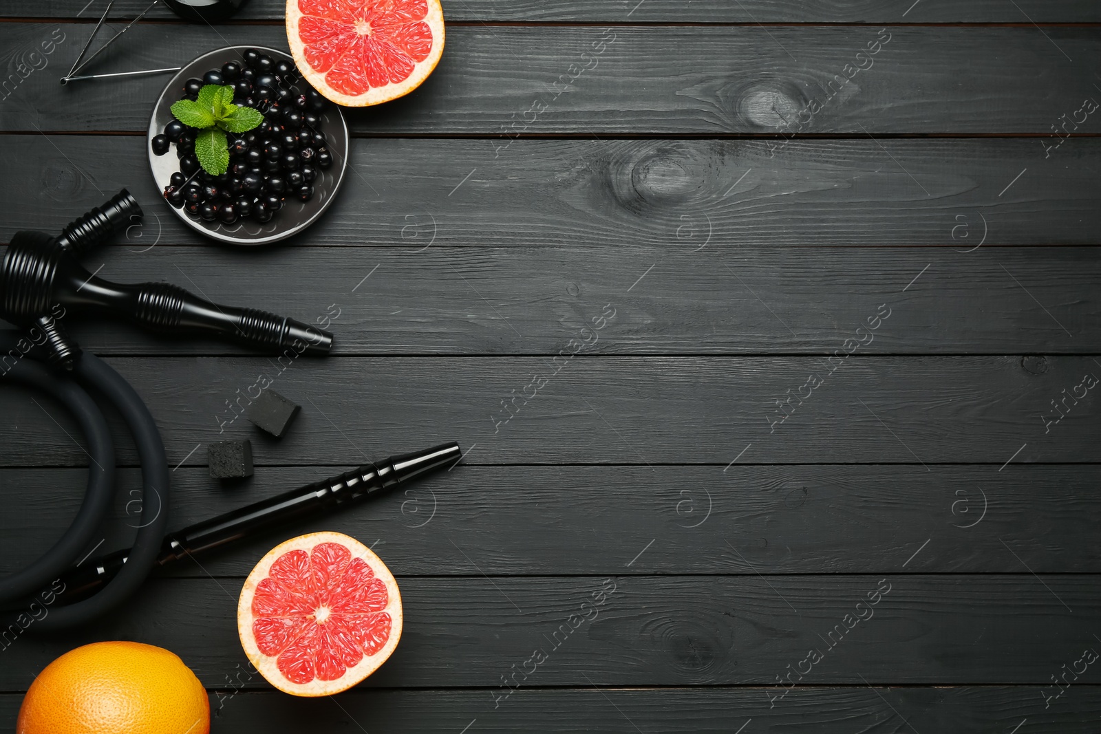 Photo of Hookah, coal and fresh fruits on black wooden table, flat lay. Space for text