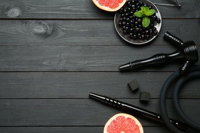 Photo of Hookah, coal and fresh fruits on black wooden table, flat lay. Space for text