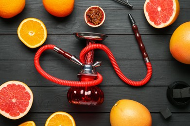 Photo of Hookah, coal and fresh fruits on black wooden table, flat lay
