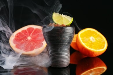 Photo of Hookah bowl with smoke and fruits on black table, closeup
