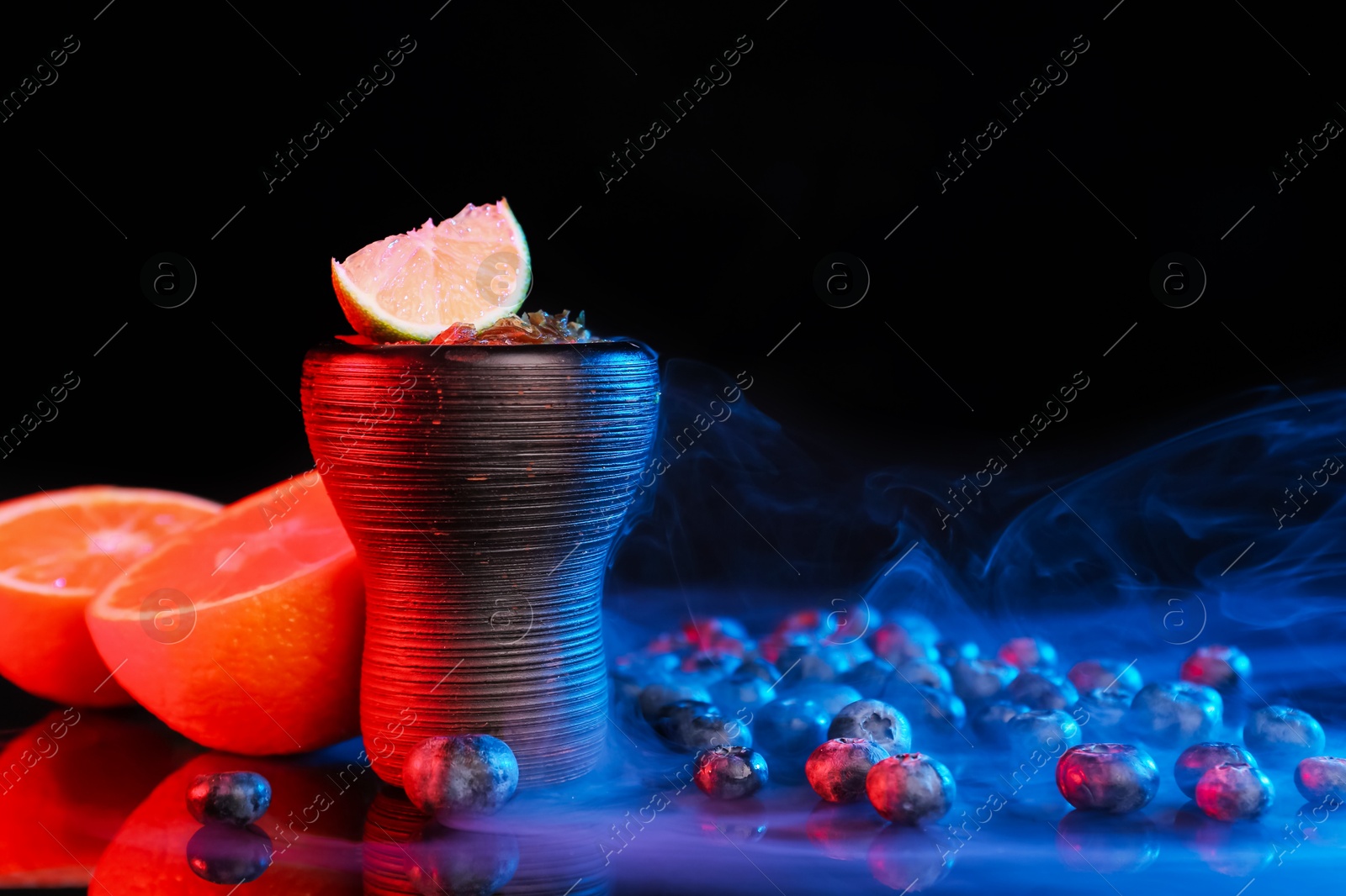 Photo of Hookah bowl with smoke and fruits on black table in neon lights, closeup. Space for text