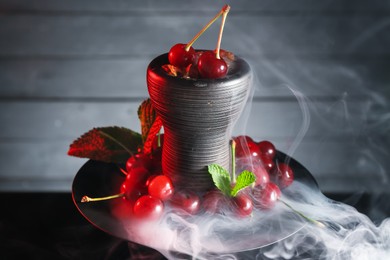 Photo of Hookah with cherries and smoke on black background, closeup