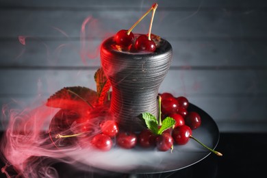 Photo of Hookah with cherries and smoke on black background, closeup