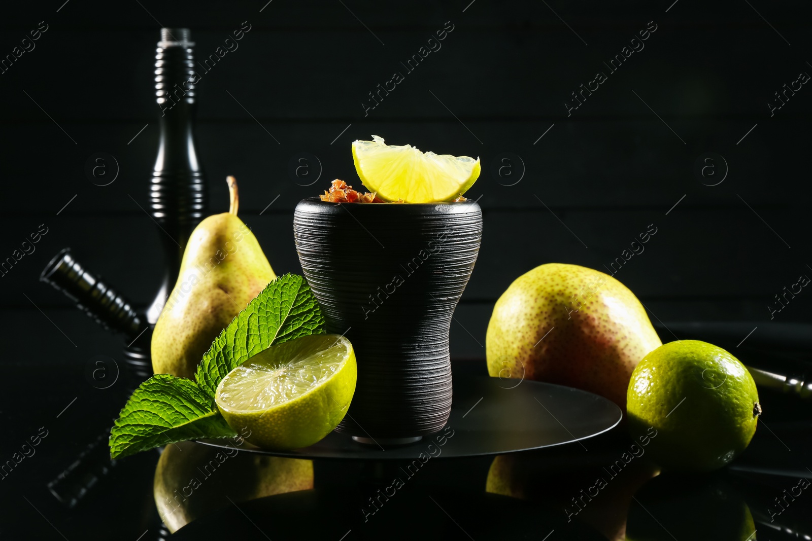 Photo of Hookah bowl with fruits, mint and smoke on black table, closeup