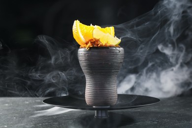 Photo of Hookah bowl with citrus fruits and smoke on black table, closeup