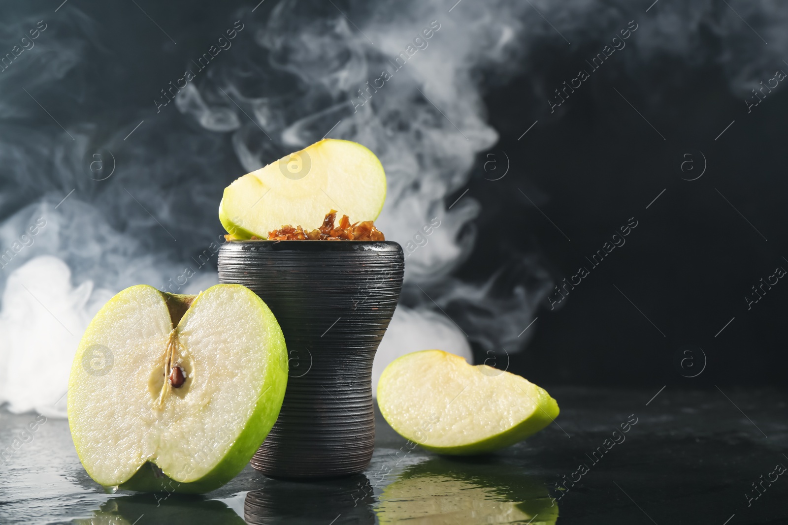 Hookah bowl with apple pieces and smoke on black table, closeup. Space for text Photo of Hookah bowl with apple pieces and smoke on black table, closeup. Space for text