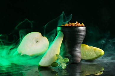 Photo of Hookah bowl with pear pieces, mint and smoke on black table, closeup