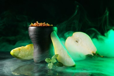 Photo of Hookah bowl with pear pieces, mint and smoke on black table, closeup