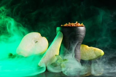 Photo of Hookah bowl with pear pieces, mint and smoke on black table, closeup