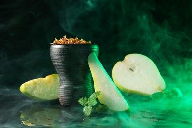 Photo of Hookah bowl with pear pieces, mint and smoke on black table, closeup