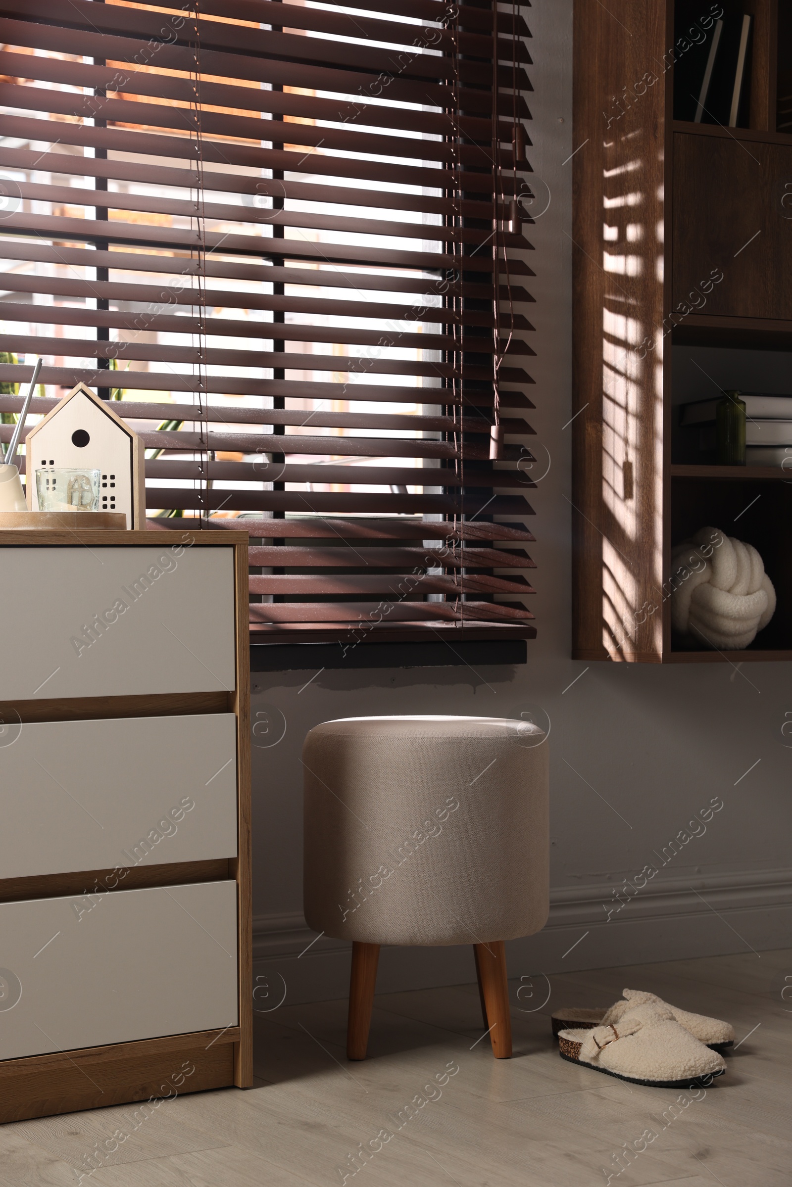 Stylish pouf and slippers near chest of drawers at home Photo of Stylish pouf and slippers near chest of drawers at home