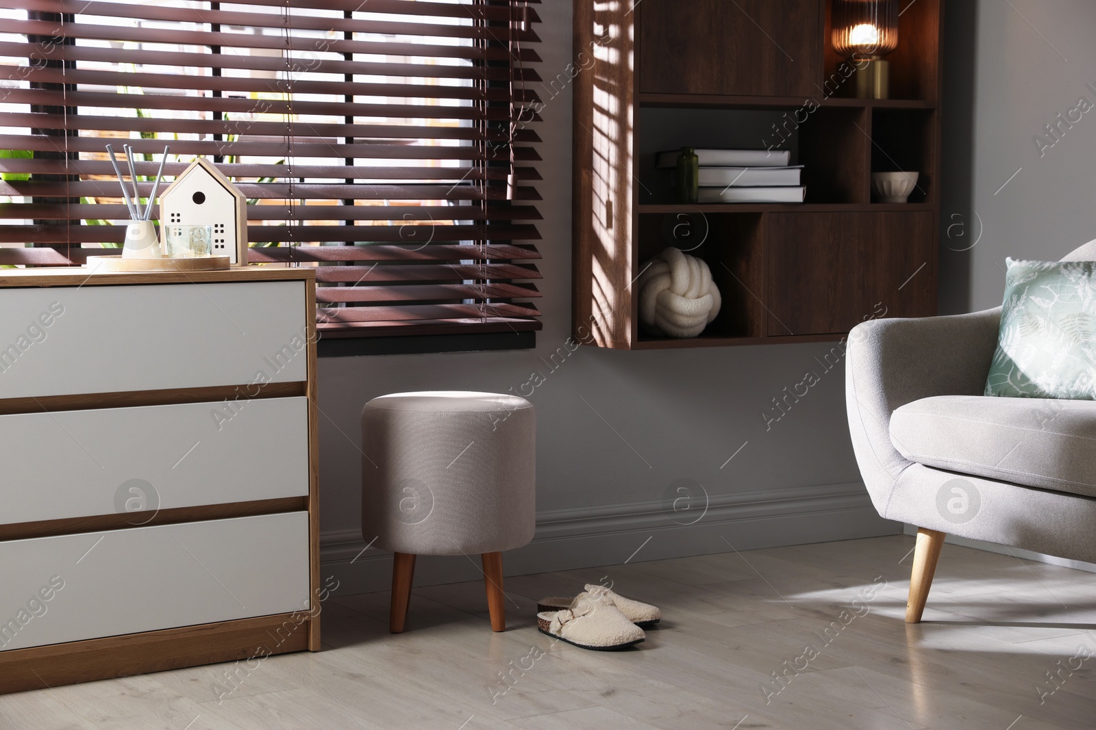 Stylish pouf and slippers near chest of drawers at home Photo of Stylish pouf and slippers near chest of drawers at home