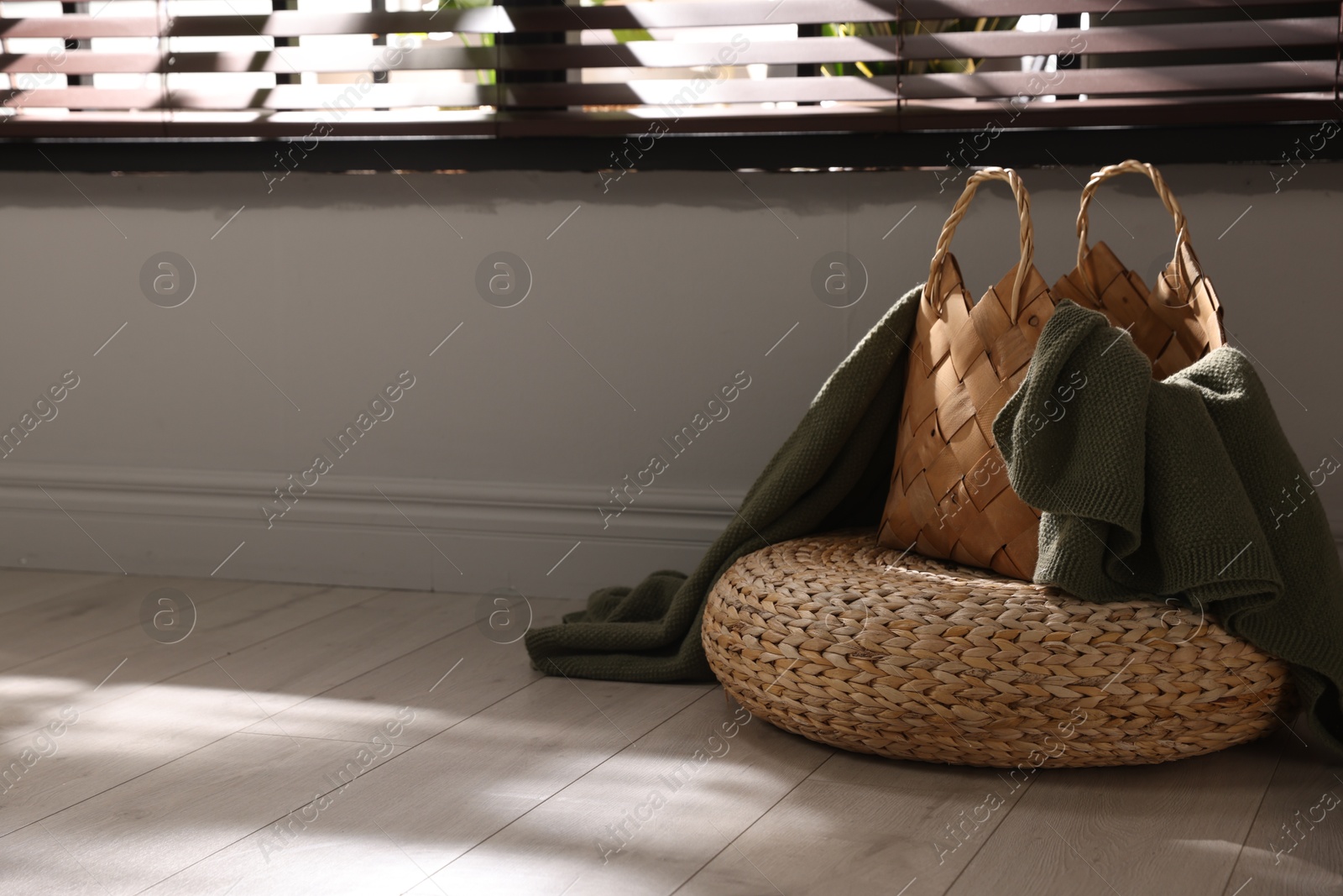 Wicker pouf and basket with plaid at home. Space for text Photo of Wicker pouf and basket with plaid at home. Space for text