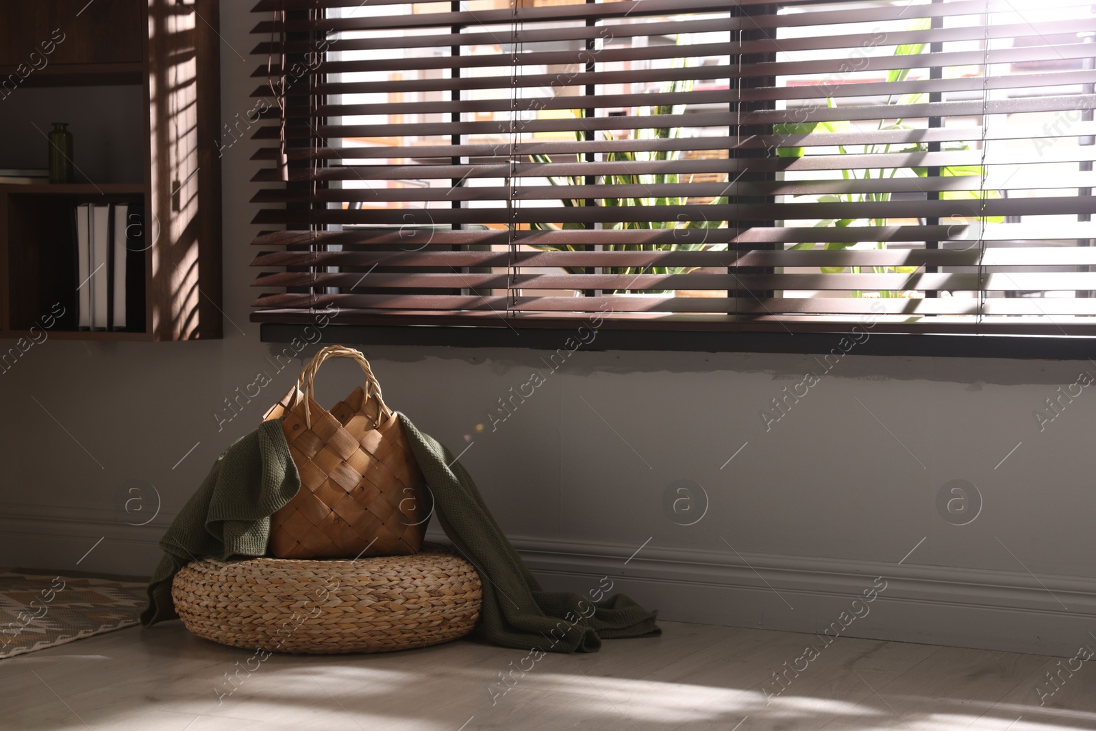 Wicker pouf and basket with plaid at home. Space for text Photo of Wicker pouf and basket with plaid at home. Space for text