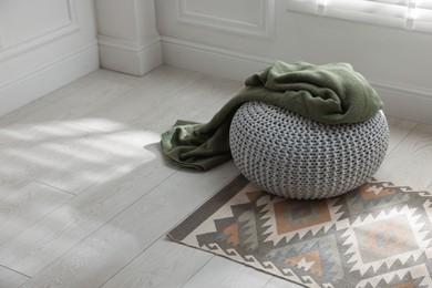 Photo of Stylish knitted pouf with plaid at home. Space for text