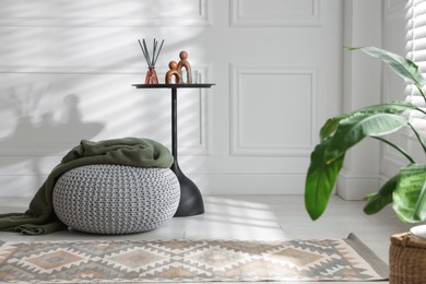 Photo of Stylish knitted pouf with plaid and home decor indoors