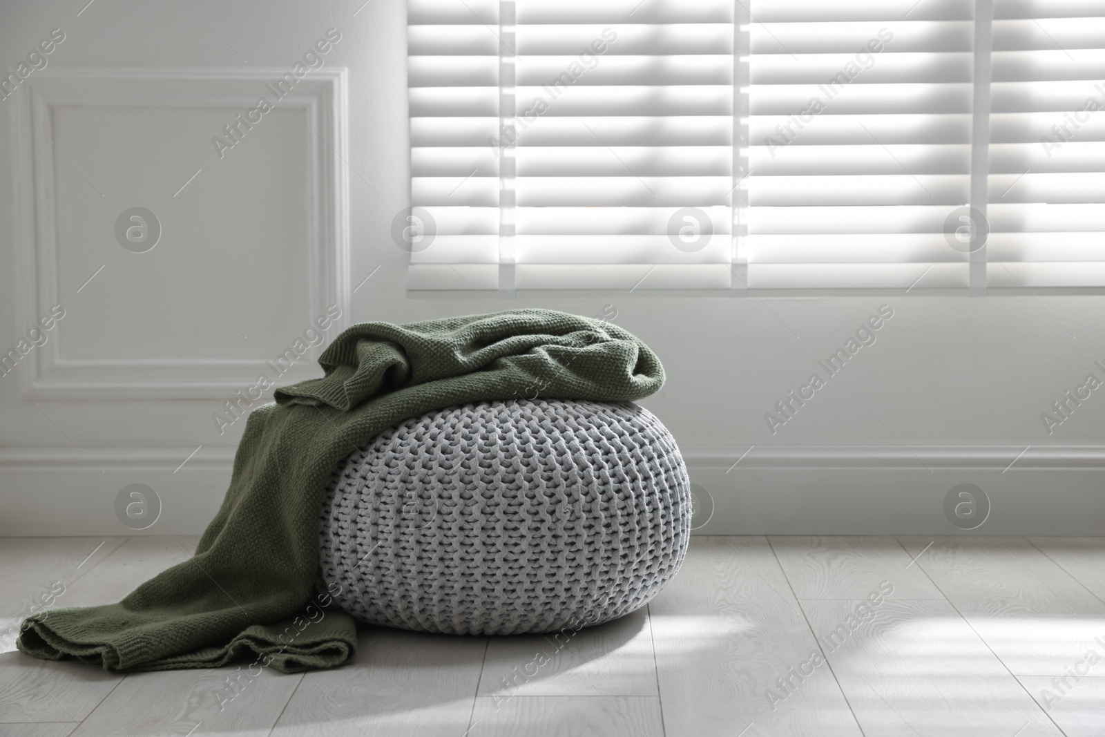 Stylish knitted pouf with plaid at home. Space for text Photo of Stylish knitted pouf with plaid at home. Space for text
