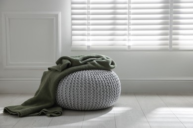 Photo of Stylish knitted pouf with plaid at home. Space for text