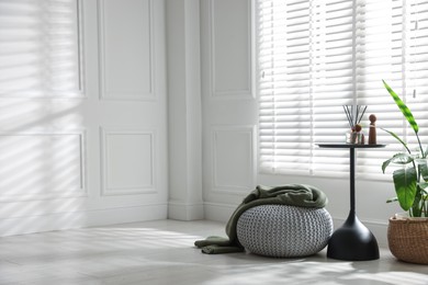 Photo of Stylish knitted pouf with plaid and home decor indoors. Space for text
