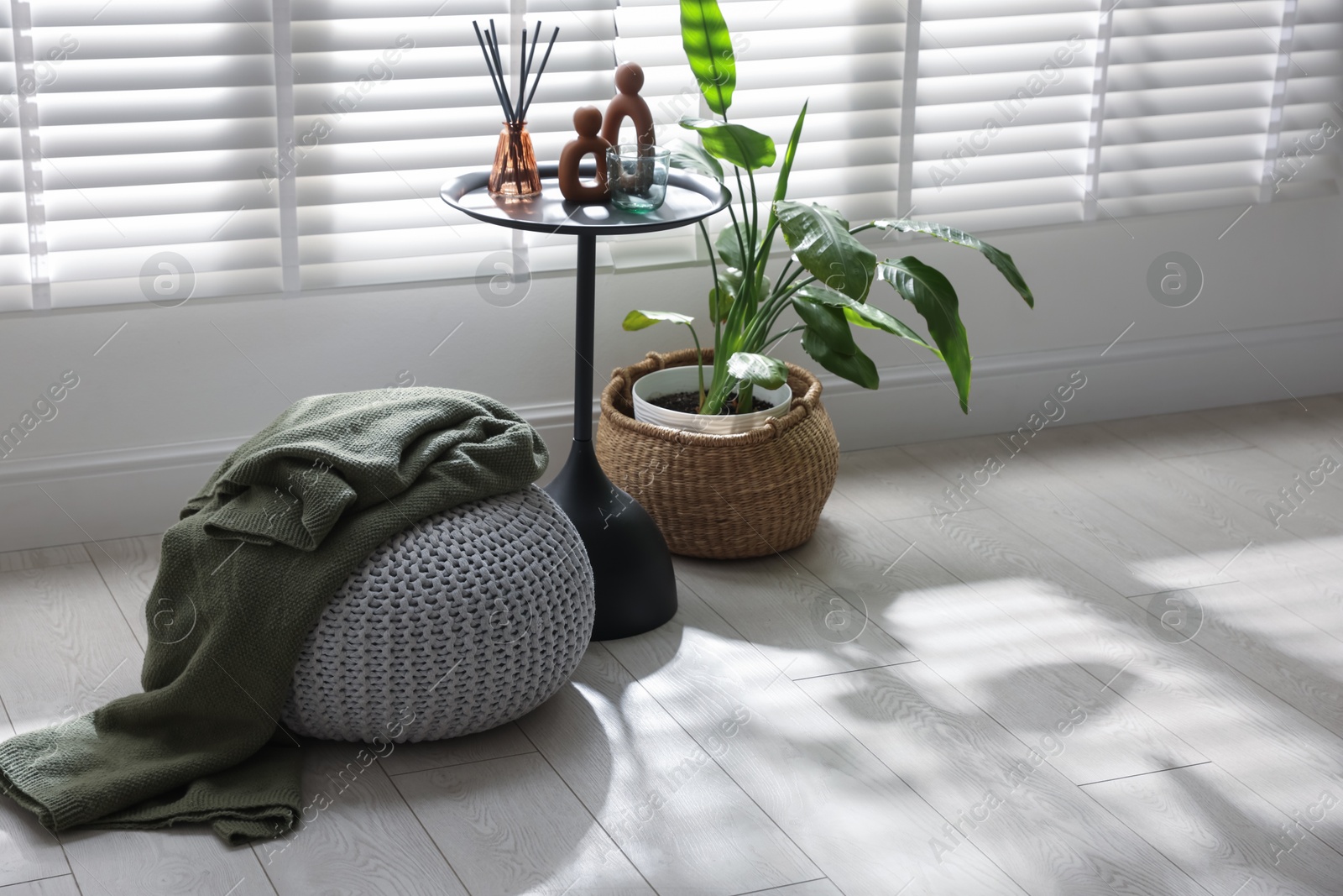 Stylish knitted pouf with plaid and home decor indoors Photo of Stylish knitted pouf with plaid and home decor indoors