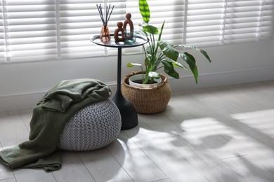 Photo of Stylish knitted pouf with plaid and home decor indoors