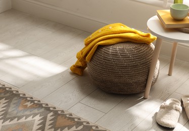 Photo of Stylish knitted pouf with sweater at home. Space for text