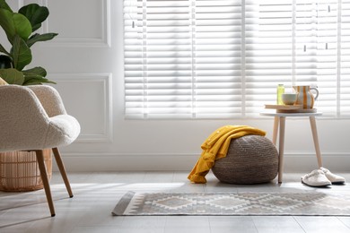 Photo of Stylish knitted pouf with sweater at home. Space for text
