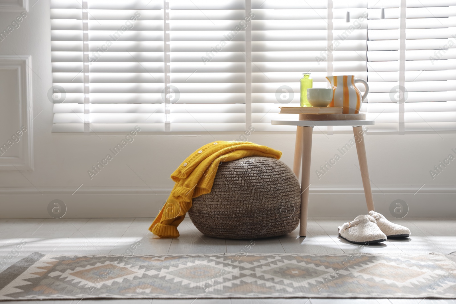 Stylish knitted pouf with sweater at home. Space for text Photo of Stylish knitted pouf with sweater at home. Space for text