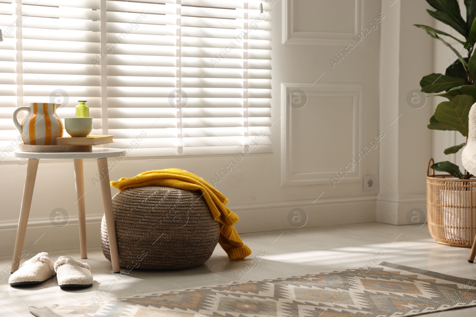 Photo of Stylish knitted pouf with sweater at home. Space for text