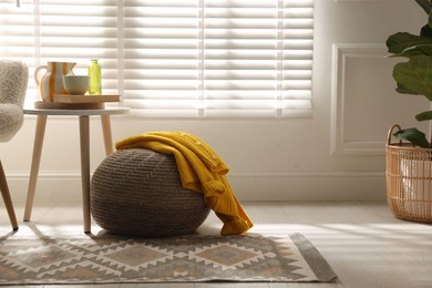 Photo of Stylish knitted pouf with sweater at home. Space for text