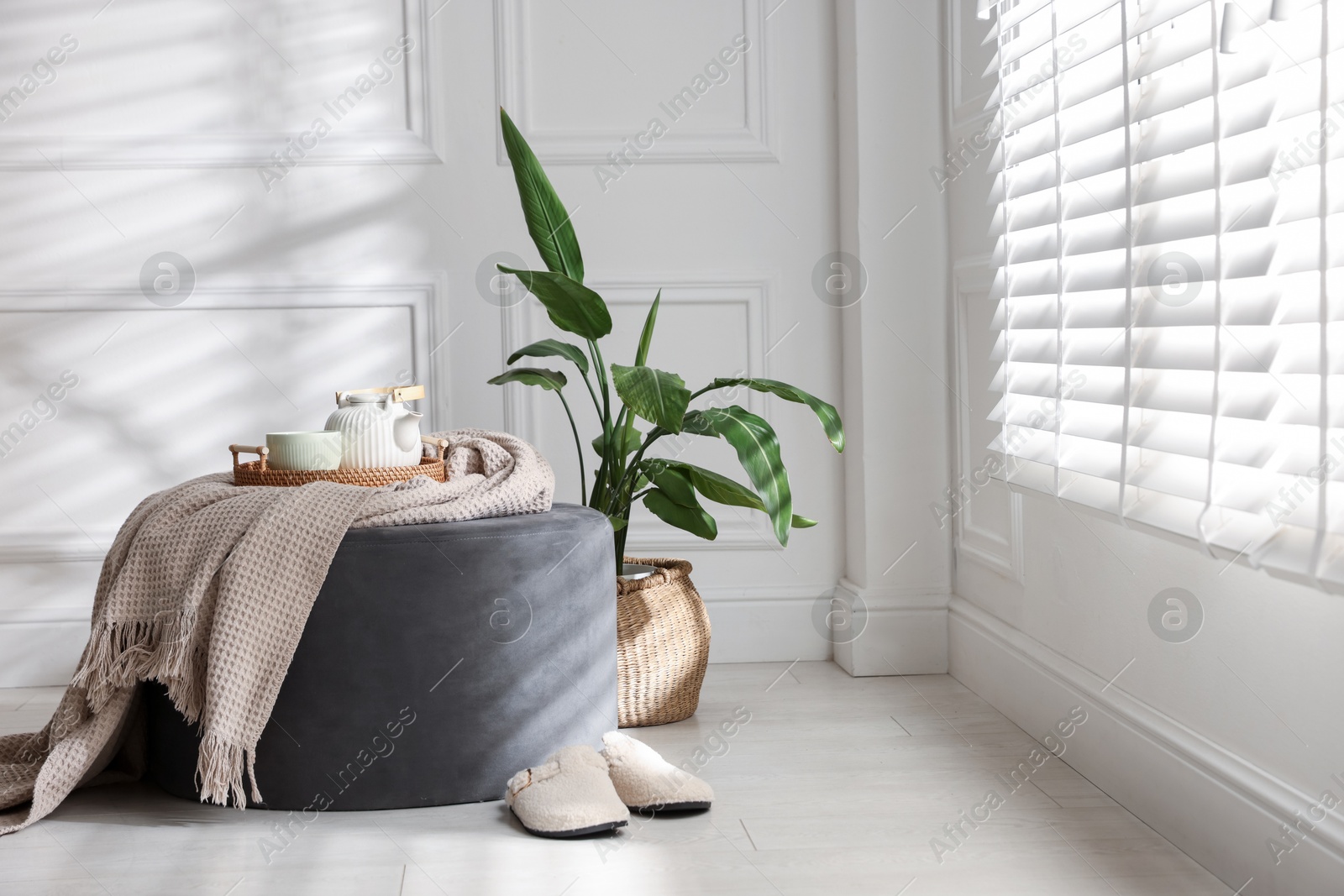 Stylish pouf with tea set at home. Space for text Photo of Stylish pouf with tea set at home. Space for text