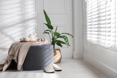 Photo of Stylish pouf with tea set at home. Space for text