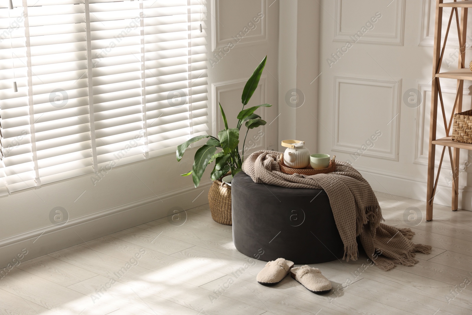 Stylish pouf with tea set at home. Space for text Photo of Stylish pouf with tea set at home. Space for text