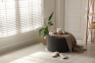 Photo of Stylish pouf with tea set at home. Space for text