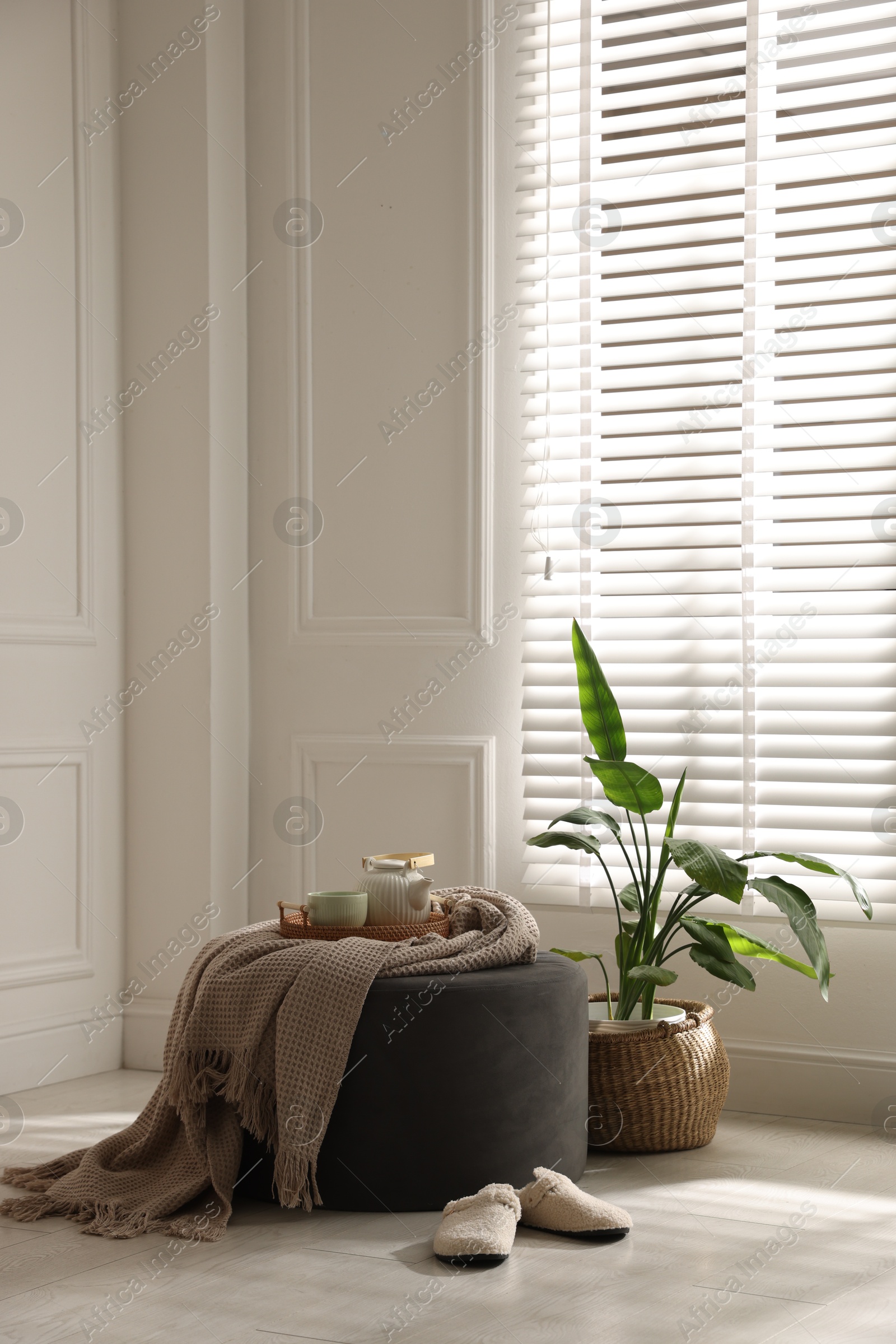 Stylish pouf with tea set at home. Space for text Photo of Stylish pouf with tea set at home. Space for text