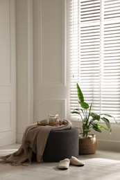 Photo of Stylish pouf with tea set at home. Space for text