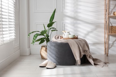Photo of Stylish pouf with tea set at home