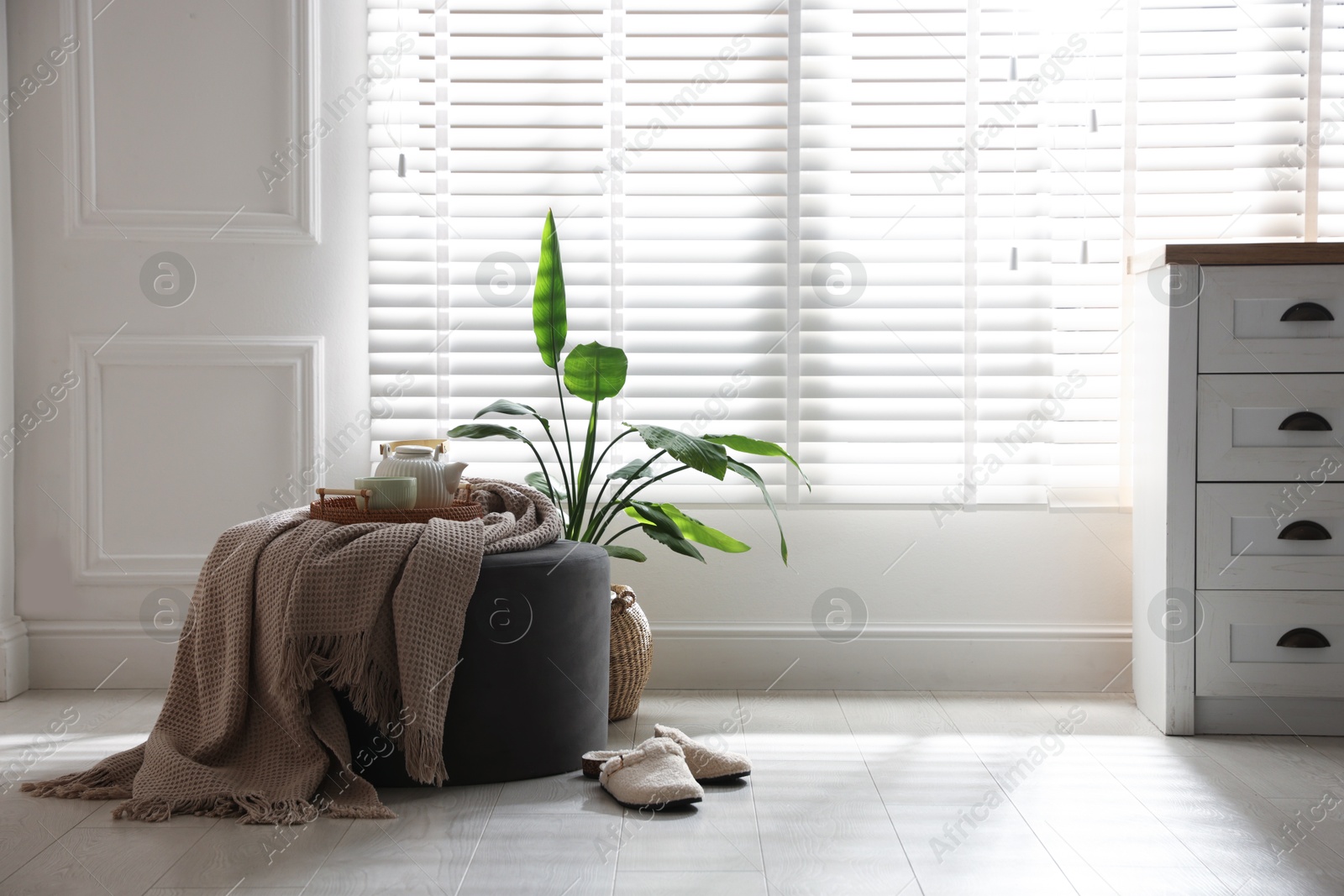 Stylish pouf with tea set at home. Space for text Photo of Stylish pouf with tea set at home. Space for text