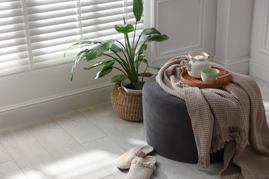 Photo of Stylish pouf with tea set at home. Space for text