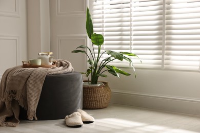 Photo of Stylish pouf with tea set at home. Space for text