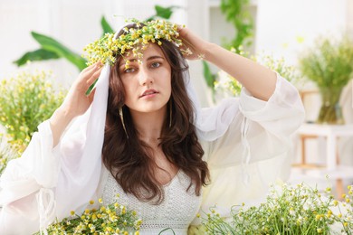 Photo of Portrait of beautiful woman with chamomile flowers indoors
