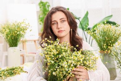 Photo of Portrait of beautiful woman with chamomile flowers indoors