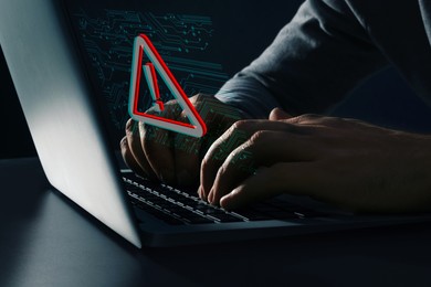 Image of Cyber attack alert notification. Red warning sign and circuit board on virtual screen. Hacker using laptop, closeup