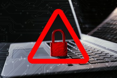 Image of Cyber attack alert notification. Red warning sign with padlock and circuit board pattern. Laptop on table, closeup