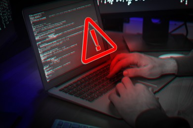 Image of Cyber attack alert notification. Red warning sign on virtual screen. Hacker using laptop, closeup
