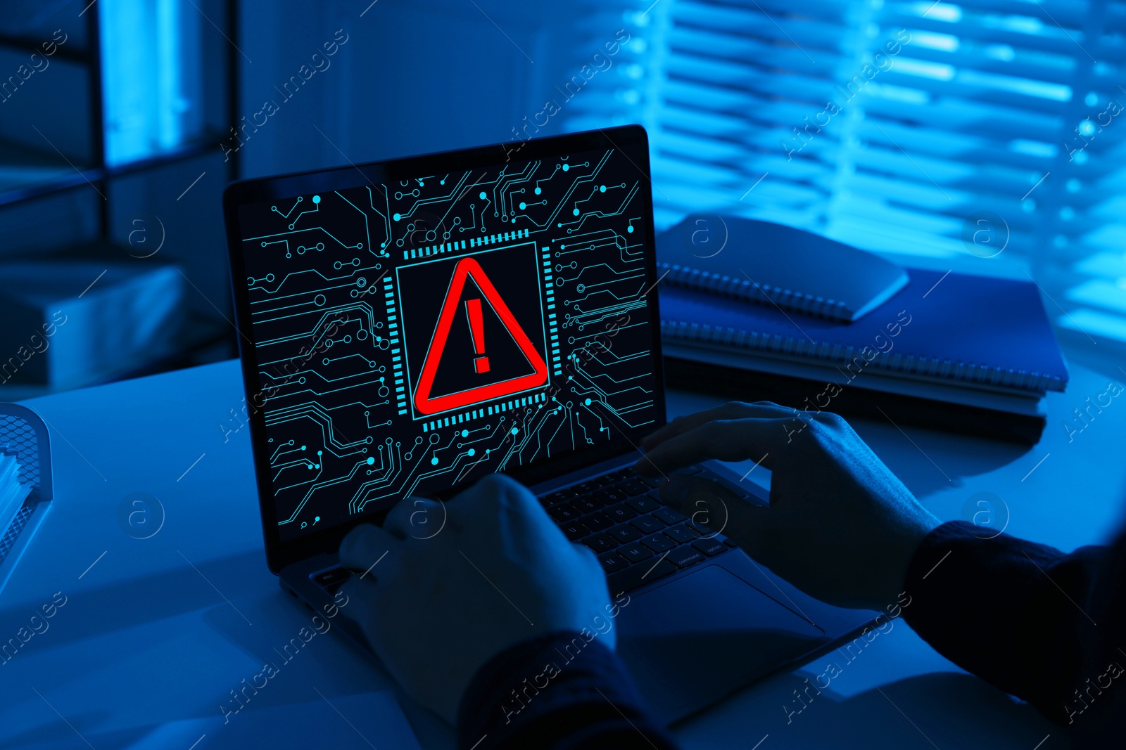 Image of Cyber attack alert notification. Red warning sign and circuit board on laptop screen. Hacker using computer, closeup