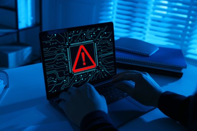 Image of Cyber attack alert notification. Red warning sign and circuit board on laptop screen. Hacker using computer, closeup