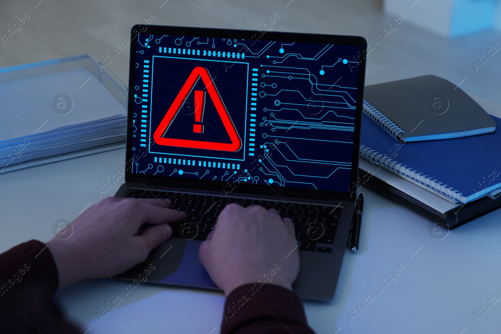 Image of Cyber attack alert notification. Red warning sign and circuit board on laptop screen. Hacker using computer, closeup